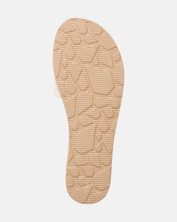 The Volcom Women's Simple Slide features a beige sole with a textured, irregular geometric pattern, shown against a plain white background that highlights its unique tread design.