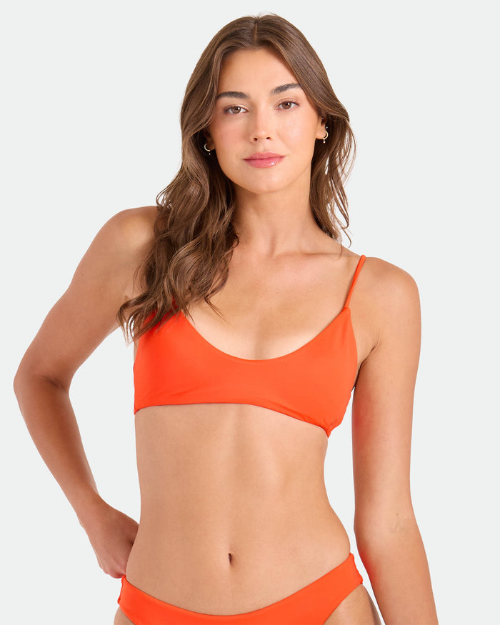 A woman with long brown hair wears the Volcom Women's Simply Seamless Bralette, standing against a plain light background and looking at the camera with a neutral expression.