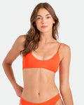 A woman with long brown hair wears the Volcom Women's Simply Seamless Bralette, standing against a plain light background and looking at the camera with a neutral expression.