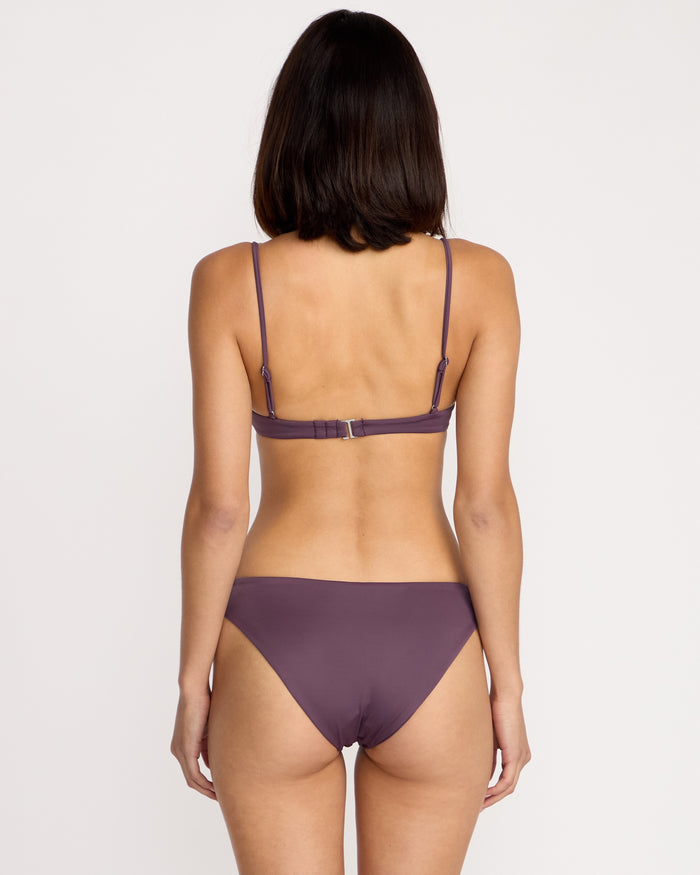 A woman with shoulder-length dark hair is shown from the back, wearing a Volcom Women's Simply Seamless Vneck bikini in purple against a plain white background.