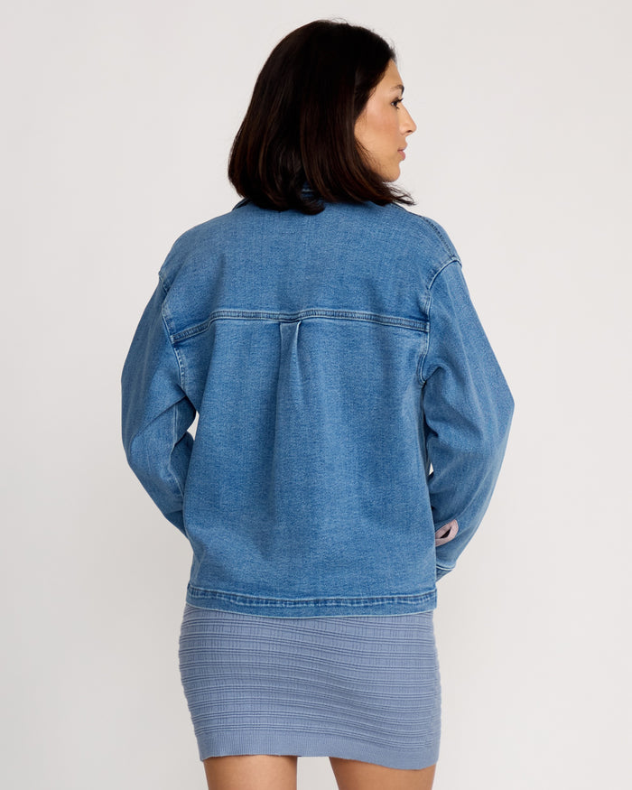A woman faces away from the camera wearing the Volcom Women's Stoned BF Shacket and a fitted gray ribbed skirt, styled against a plain white background.