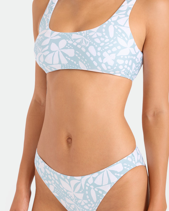 A woman models the Volcom Women's Tribal Stone Hipster Full Bikini Bottom, featuring a light blue and white pattern in the Summer Song color, made from recycled nylon. Shown from shoulders to upper thighs against a plain background; her face isn't visible.