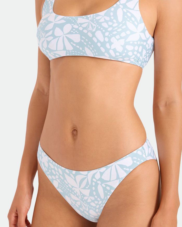 A model wears the Volcom Women's Tribal Stone Scoop Bralette, crafted from recycled nylon in a light blue and white pattern, shown from shoulders to upper thighs against a plain light background.