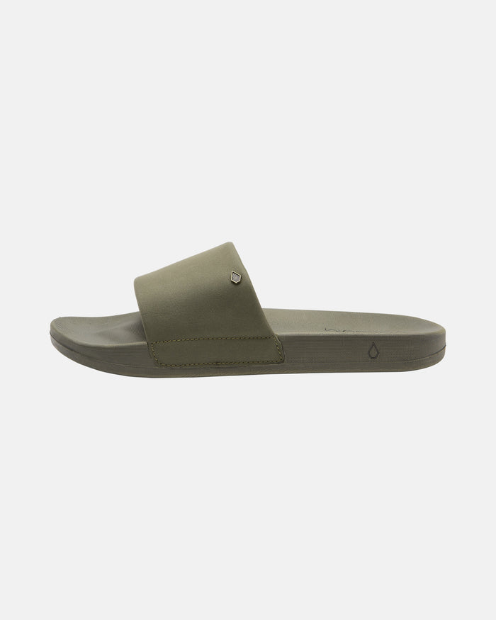 The Volcom Women's Volcation Slides feature an olive green wide strap and flat sole for everyday comfort, shown against a plain white background.
