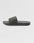 The Women's Volcation Slides by Volcom are black slide sandals featuring a wide single strap and flat sole for everyday comfort, ideal for summer wear. Shown against a white background.