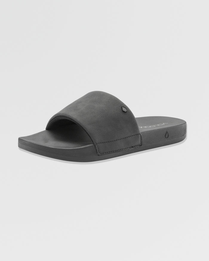 The Volcom Women's Volcation Slides are black summer sandals with wide straps and flat soles, designed for everyday comfort, shown at a slight angle on a plain white background.