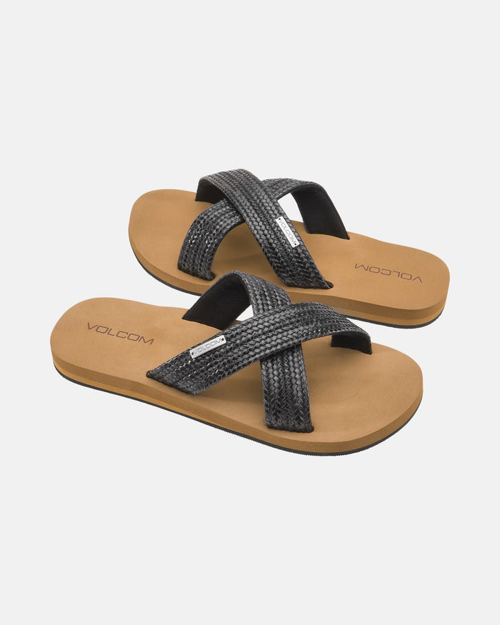 Women's Volcom Double Cross Sandals feature tan footbeds and black textured crisscross fabric straps, shown against a white background.