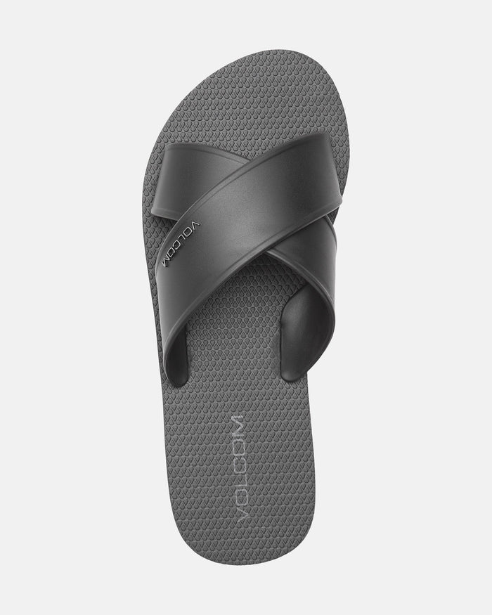 The Women’s Volcomotion Strap Sandals by Volcom feature a single gray sandal with a textured footbed and two wide, crisscrossing black straps, branded with "VOLCOM" on both the strap and footbed, shown against a plain white background.