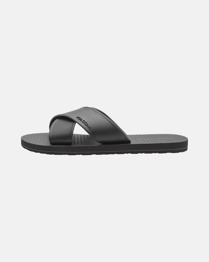 The Women's Volcomotion Strap Sandals by Volcom feature a black crisscross strap, textured footbed, flat sole, and a subtle logo on the strap, shown against a plain light background.