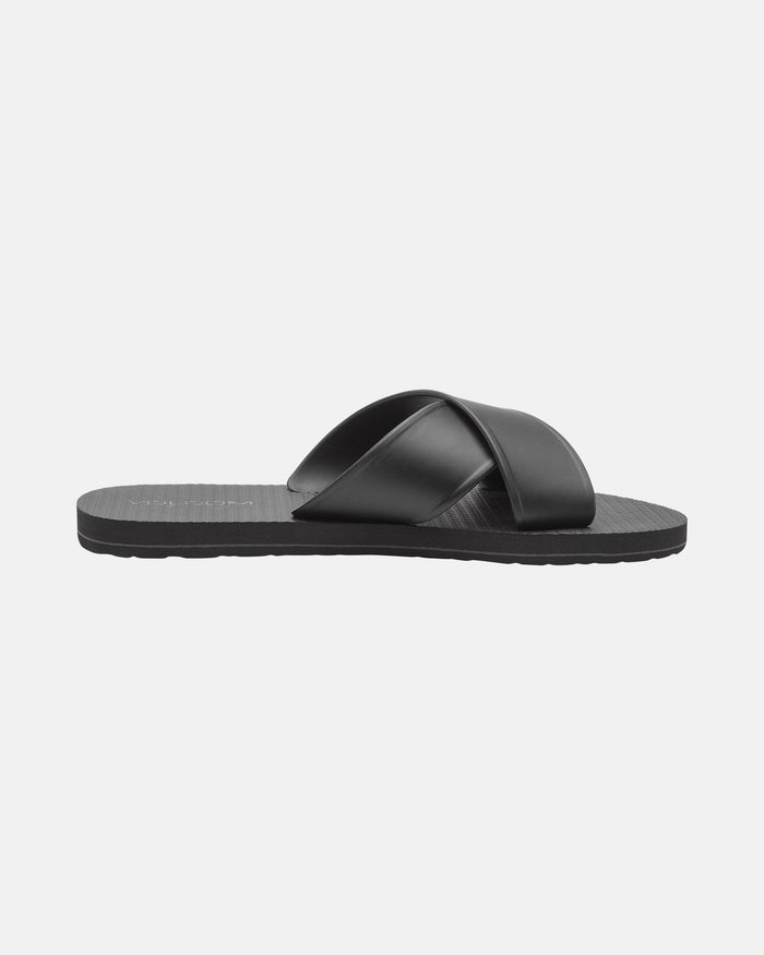 The Women's Volcomotion Strap Sandals by Volcom are black flats featuring two wide, overlapping straps across the top, shown on a plain white background.