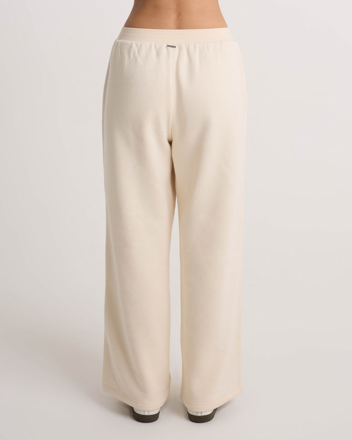 A person wears Volcom Women's Wide Leg Sweatpants in a loose, cream-colored style, shown from the back against a plain white background. These sweatpants feature a relaxed fit with wide legs and an elastic waistband that sits comfortably at the waist.